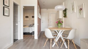 Un espacio de estar moderno y de concepto abierto con comedor, una cama y un pasillo que conduce a otra habitación.