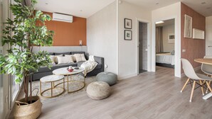 Una sala de estar moderna con un sofá gris, una mesa de centro redonda y una planta grande.