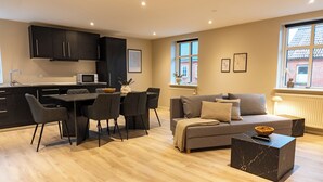 A modern living space with a kitchen, dining area, and seating area. - Hotel Ulfborg (Ulfborg)