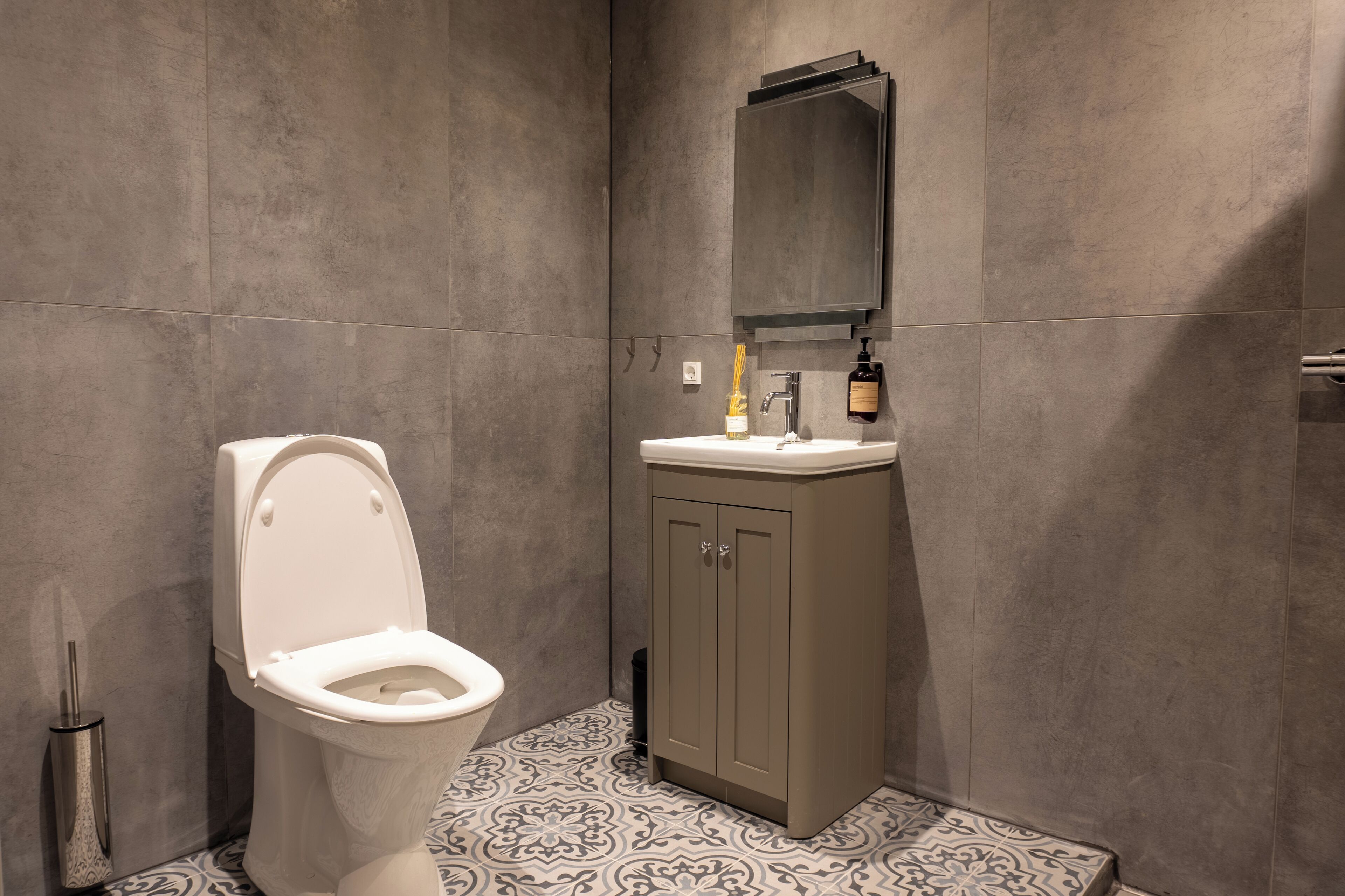 A modern bathroom with a toilet, sink, and mirror.