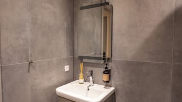 Un bagno con un lavandino bianco, uno specchio e un erogatore di sapone.