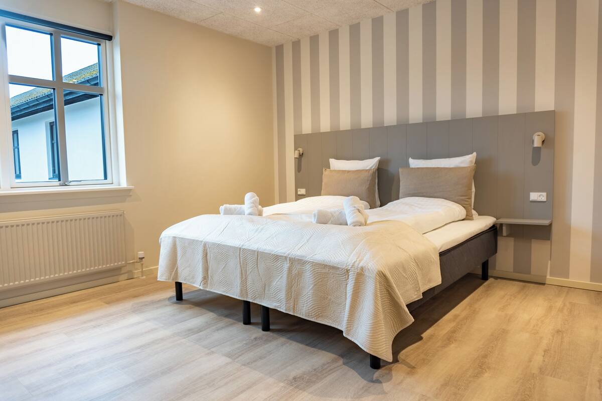 Ein modernes Schlafzimmer mit einem großen Bett, einer Heizung, einem Fenster und rauen Wänden.