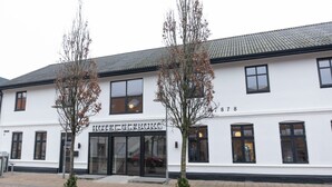 A white building with the sign "HOTEL ULFBOURG" and a staircase leading to the entrance. - Hotel Ulfborg (Ulfborg)