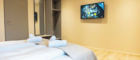 A hotel room with a bed, a TV mounted on the wall, and a wardrobe.