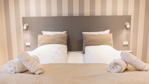 A neatly made bed with two pillows, a headboard, and two wall-mounted lights. - Hotel Ulfborg (Ulfborg)