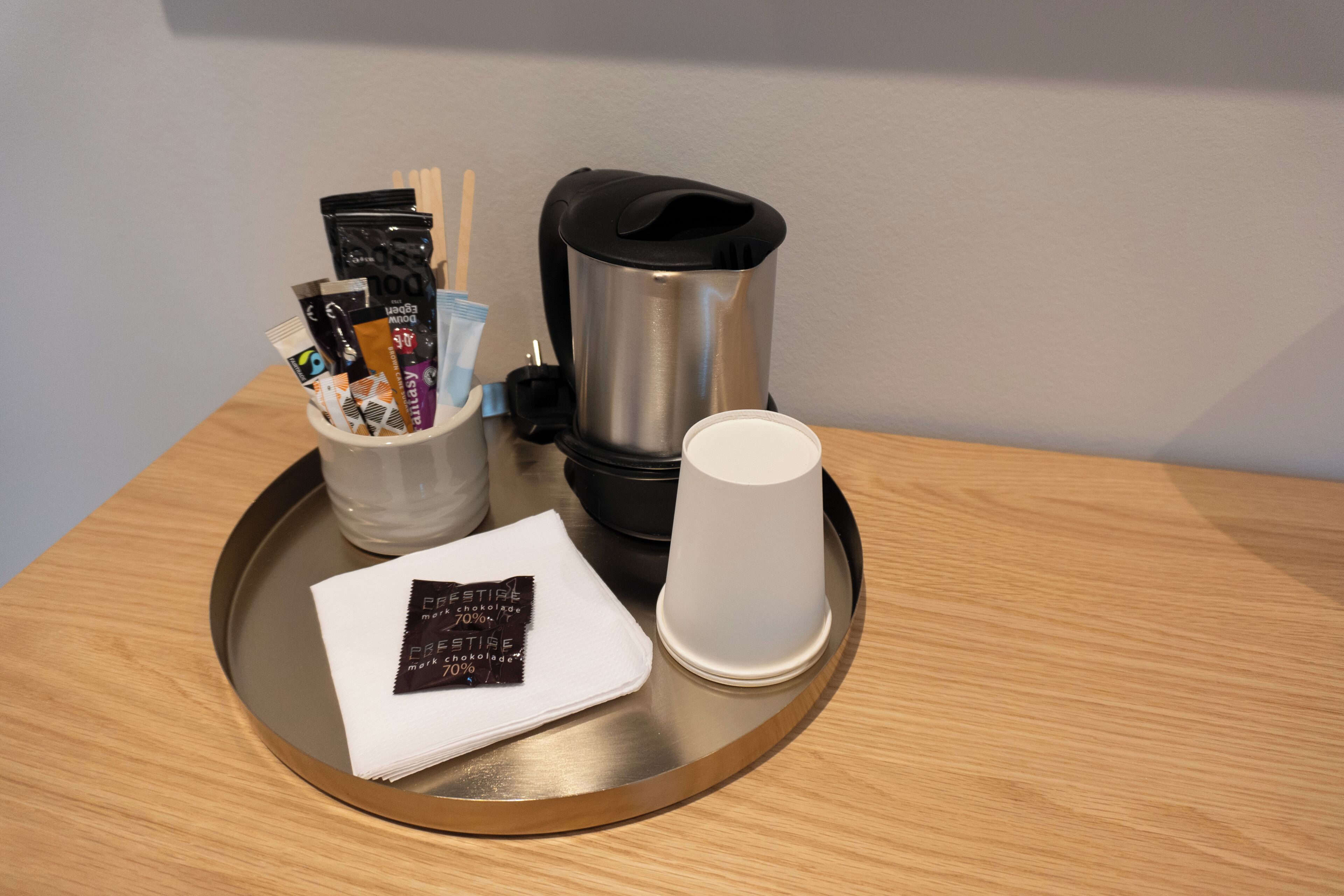 Una bandeja con una cafetera, una taza, una servilleta y una barra de chocolate.
