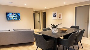 A modern dining area with a dark marble table, grey upholstered chairs, and a woven basket centerpiece. - Hotel Ulfborg (Ulfborg)