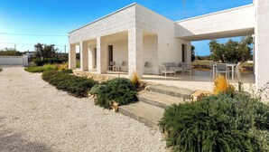 A modern building with a covered patio area, outdoor seating, and a gravel pathway. - Borgo Morgicchio by Perle di Puglia (Carovigno)