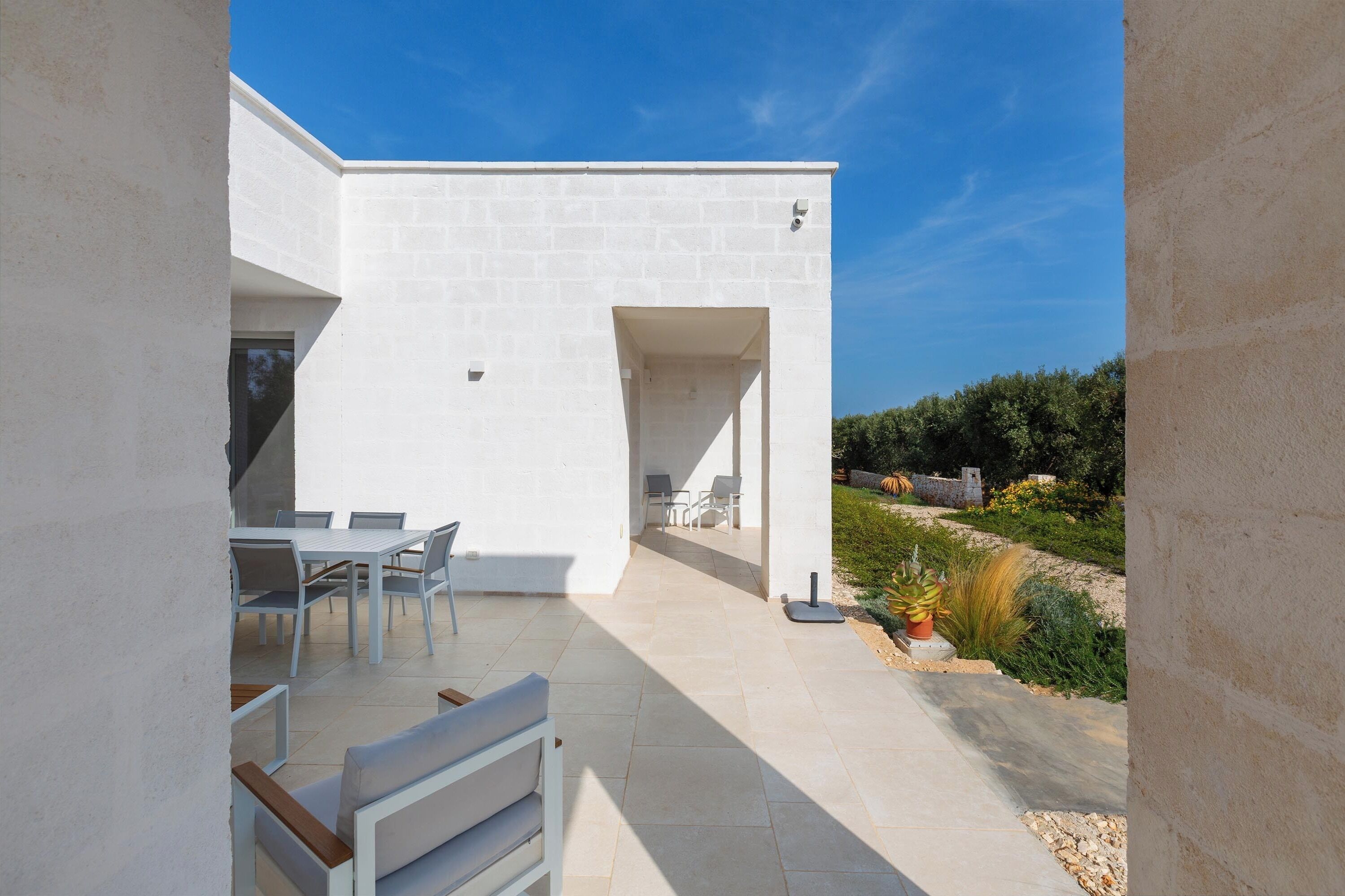 Eine moderne Außenpatio mit weißen Wänden und wolkenlosem, blauem Himmel.