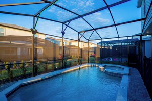 A swimming pool with a glass enclosure, surrounded by a landscaped garden and a brick pathway.