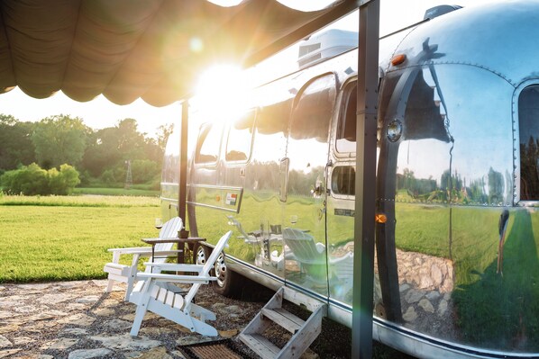 A trailer with a covered porch, a table, and chairs.