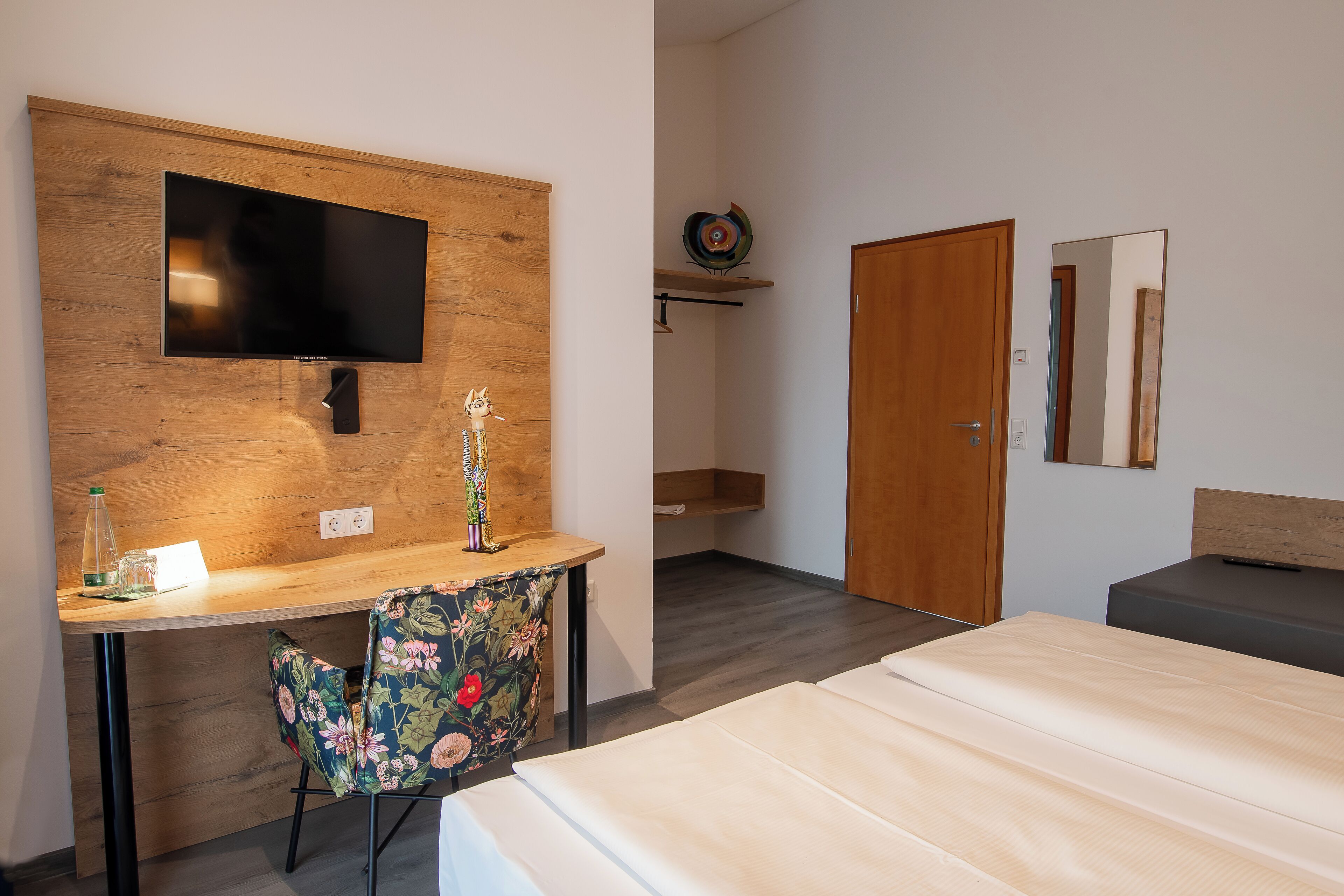 Habitación de hotel con escritorio de madera, televisor, cama y una silla.
