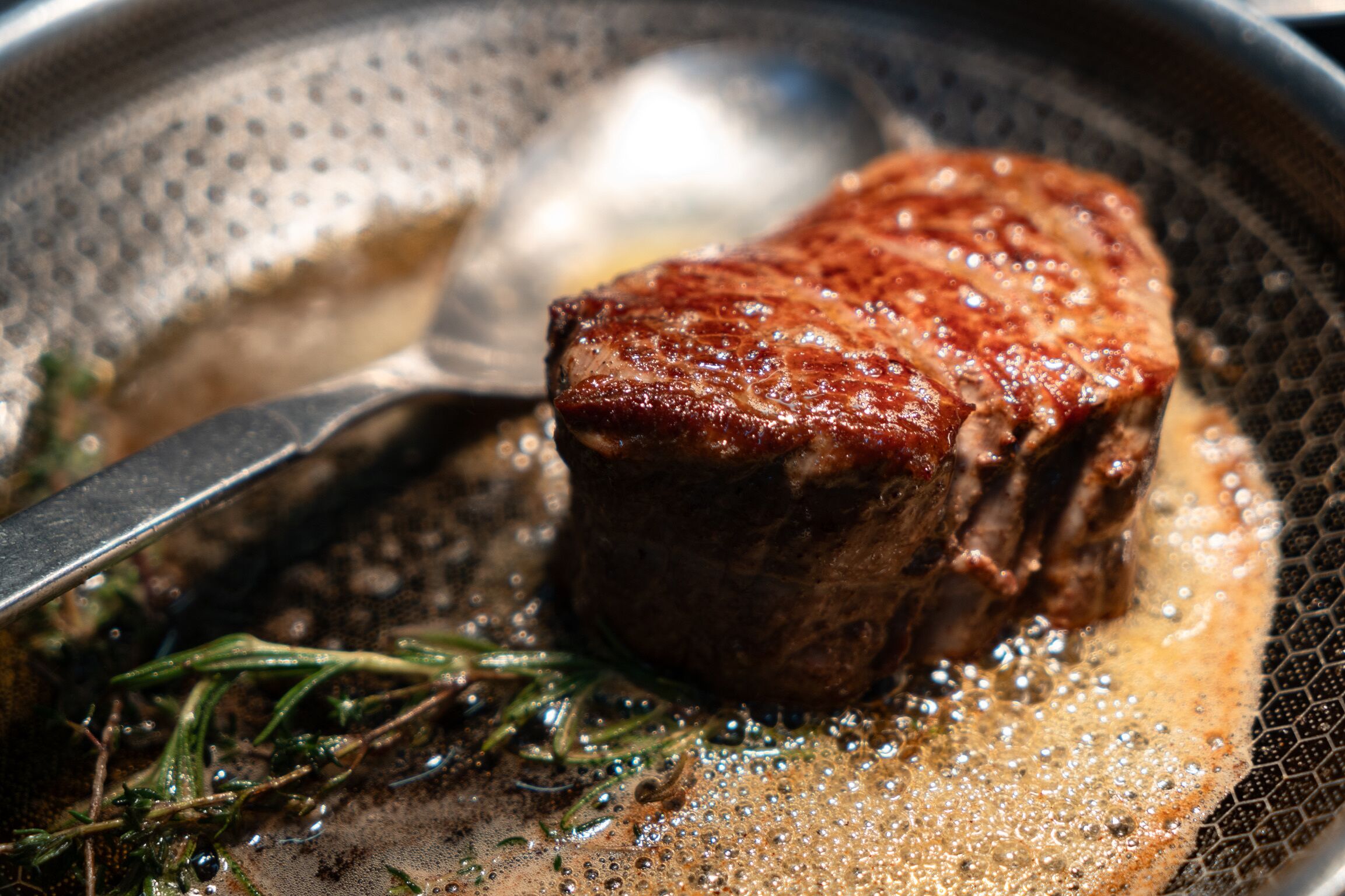 Un bistec cocinándose en una sartén con un tenedor.