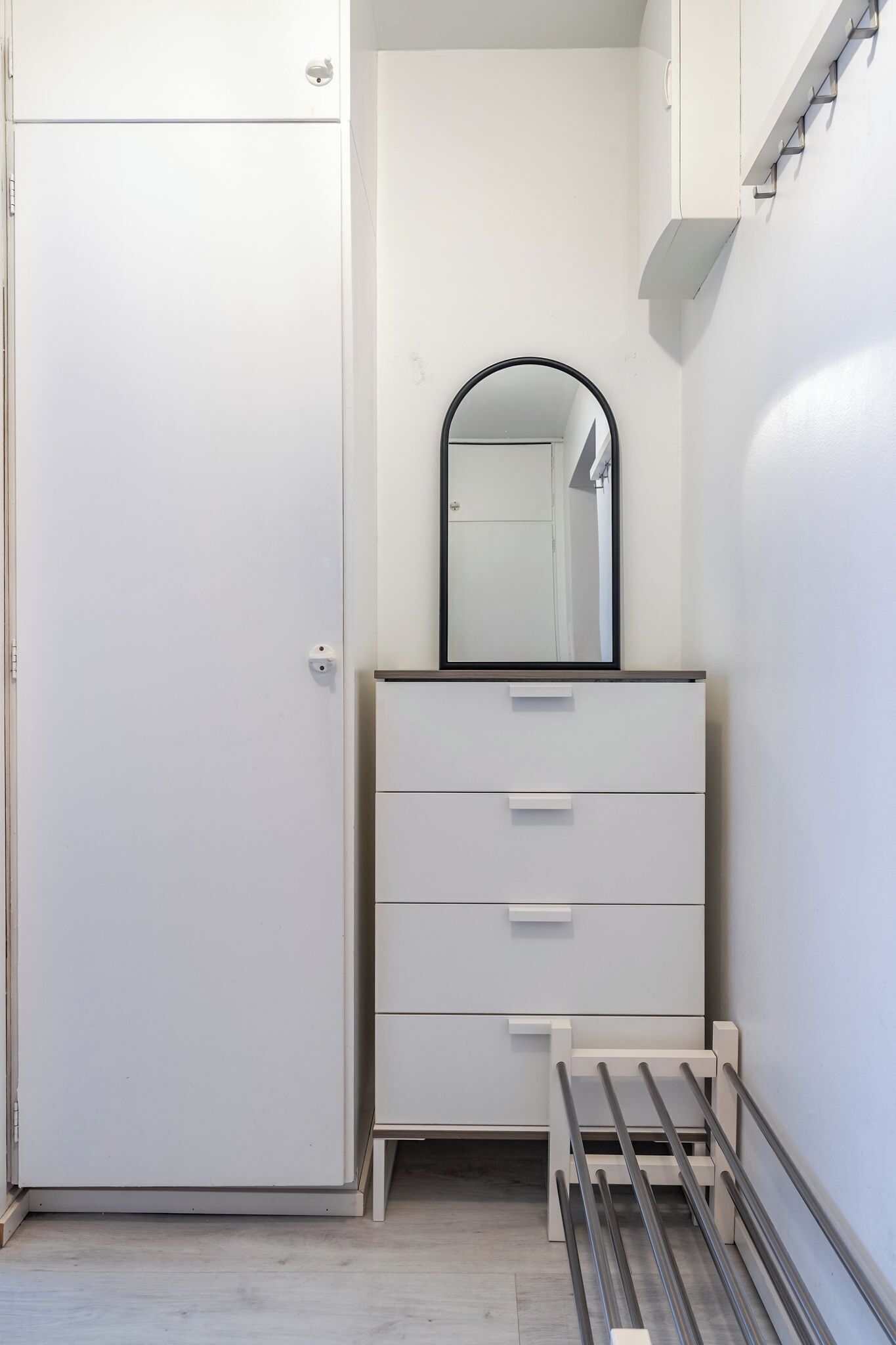 A white wardrobe with a mirror, a bench, and a small table.