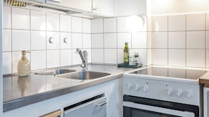Una cocina moderna con armarios blancos, electrodomésticos de acero inoxidable y un horno empotrado.
