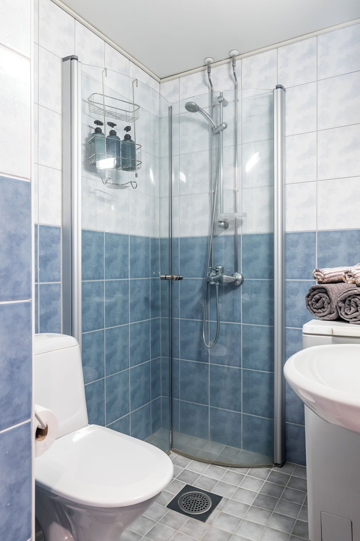 A bathroom with a glass-enclosed shower, a toilet, and a sink.