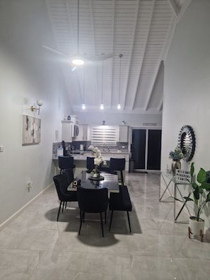 A modern kitchen with white cabinets, a dining area with a glass table and black chairs, and a ceiling with exposed beams. - 

Fairway Estate, 10 mins to Ochi.  3 bedroom, 4 beds 3 bath hse. Private Beach (Drax hall)