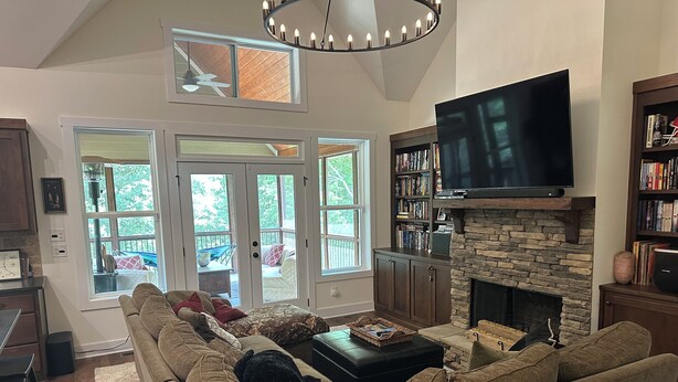 A living room with a sectional sofa, a fireplace, a TV, and a bookshelf.