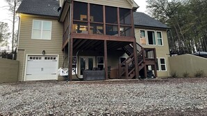 A two-story house with a balcony, a garage, and a gravel driveway.