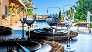 Ein Tisch mit Weingläsern, Tellern und Besteck, mit Blick auf einen Pool und üppiges Grün.