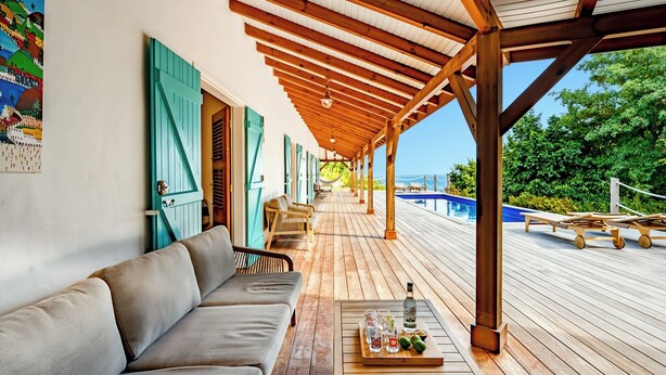 Ein überdachter Außenbereich mit Pool, Holzterrasse und einer Sitzecke.