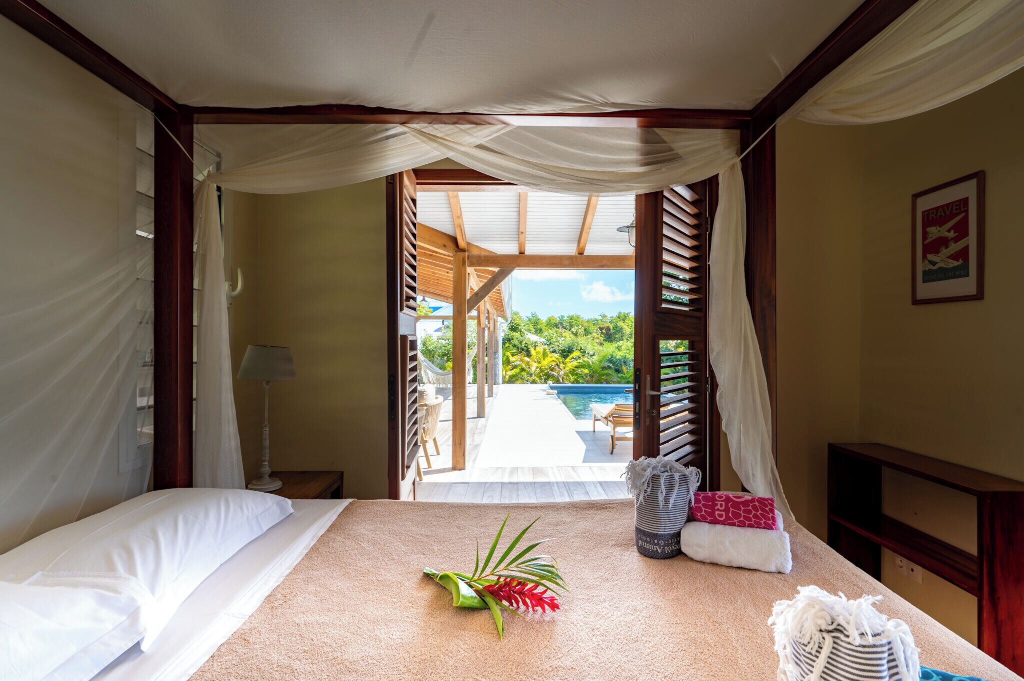 Une chambre avec un lit, une table de chevet, une lampe et une vue sur une piscine et un espace extérieur.