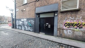 A building with a black door, a brick facade, and graffiti on the walls.