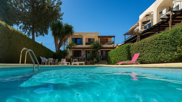 A swimming pool with clear blue water, surrounded by lounge chairs and a building with a balcony. - Ibiscus pool –5 min Walk to Beach & Pafos Harbour (Paphos)
