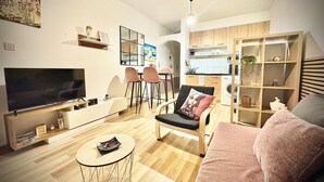 A modern living room with a flat-screen TV, a sofa, a coffee table, and a dining area with chairs. - Ibiscus pool –5 min Walk to Beach & Pafos Harbour (Paphos)