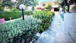 A pathway lined with lush greenery and flowering plants, leading to a building with a traditional architectural style. - Ibiscus pool –5 min Walk to Beach & Pafos Harbour (Paphos)