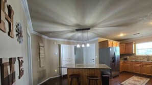 Una cocina amplia con una isla central, armarios de madera y un refrigerador grande.
