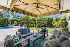 A covered outdoor seating area with a ceiling fan, a pool, and lush greenery in the background. - Miami Dream Home with Pool (North Miami)