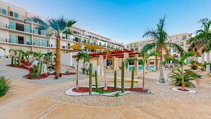 A hotel courtyard with palm trees, a pool, and a covered seating area. - Apartment C25, if you are looking for tranquility, this is the right place for you!  (San José del Cabo)