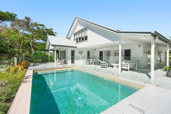 Uma casa moderna com piscina, fachada branca e portas de vidro.