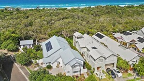 Un quartier résidentiel avec des maisons, des panneaux solaires et une vue sur l’océan.