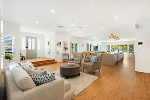 A spacious living room with a sofa set, a coffee table, and a dining area with chairs.