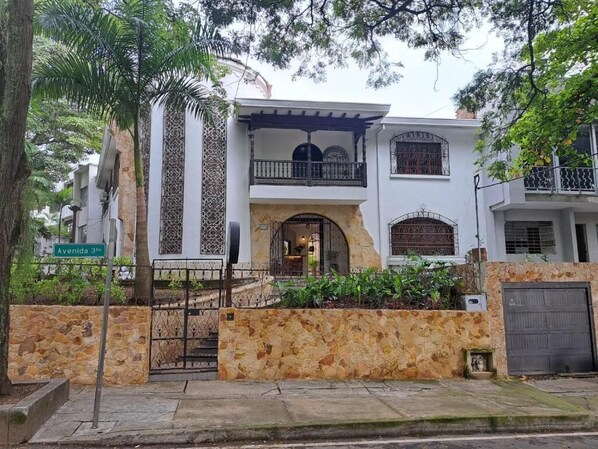 A two-story house with a stone facade, a balcony, and a gated entrance. - Casa Sileo (Cali)
