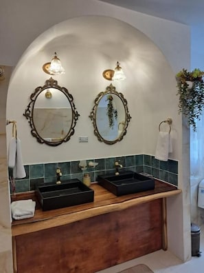 Un baño con dos espejos, un tocador de madera y un salpicadero de azulejos verdes.