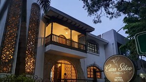 Um edifício de dois andares com varanda, placa indicando Casa Sileo Boutique Hotel e grade de ferro forjado.