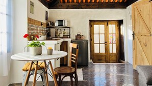 Una cocina acogedora con techo de madera, una mesa blanca con sillas y un refrigerador.