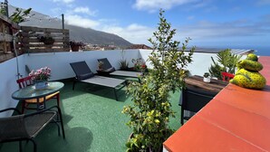 Terraza en la azotea con vistas a una montaña, una valla de madera y plantas en macetas.