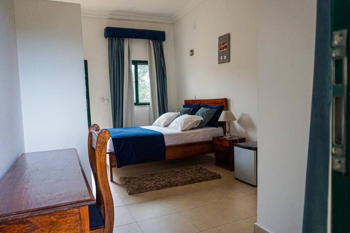 A bedroom with a bed, bedside table, lamp, and a small desk.