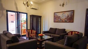 Un salon avec des canapés, une table basse et un meuble. Il y a un tableau au mur et un lustre.