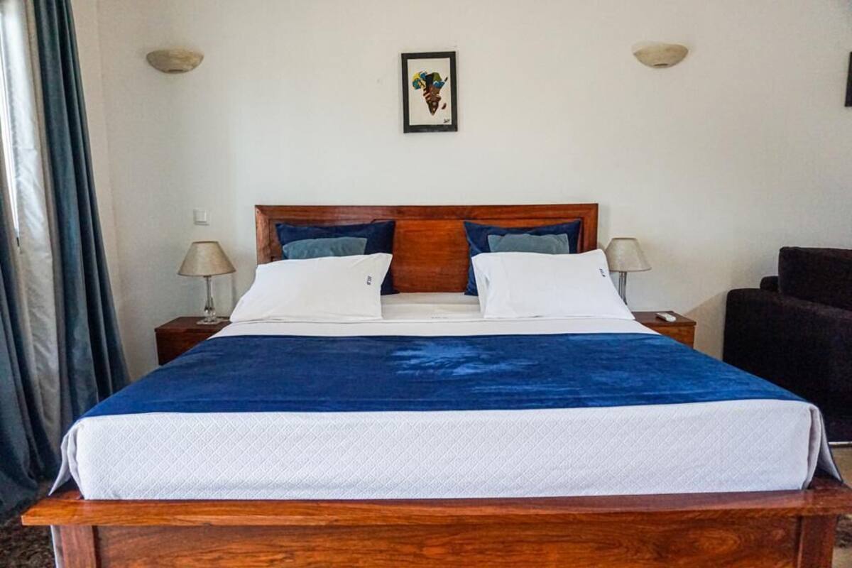A neatly made bed with a blue and white bedspread, two bedside lamps, and a framed picture on the wall.