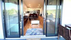 A modern living room with a sofa, a coffee table, and a view of the kitchen through glass doors. - Amazing 180° Lake Views | Boat Slip | 2-Min SDC (Branson)