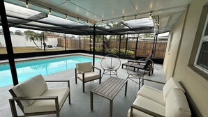 A covered patio area with a pool, outdoor furniture, and a view of the backyard.
