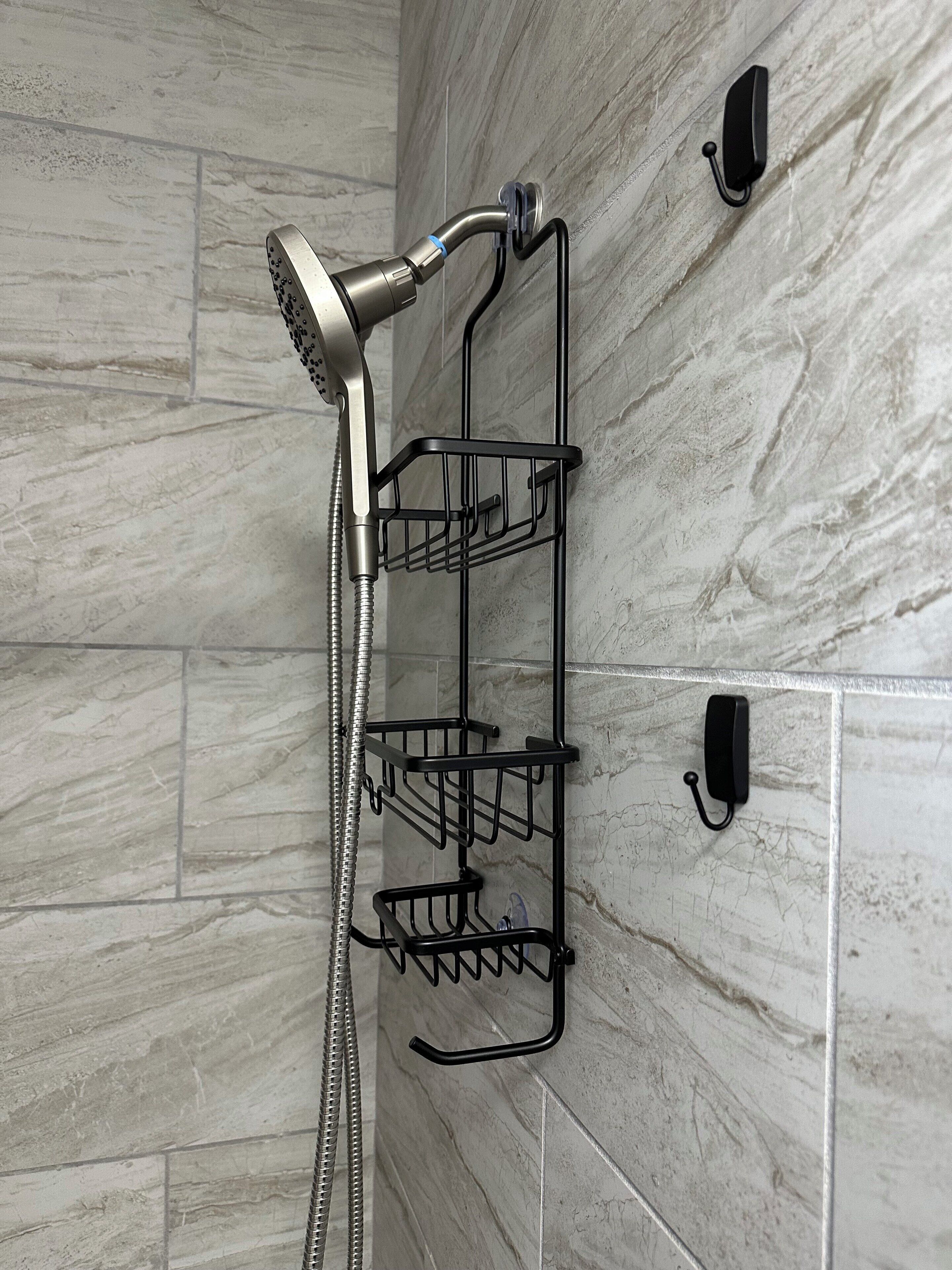 Une douche équipée d’un pommeau de douche à main et d’une étagère en métal noir dotée de plusieurs crochets.