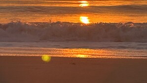 Um pôr do sol sobre o oceano com ondas avançando em direção à praia.