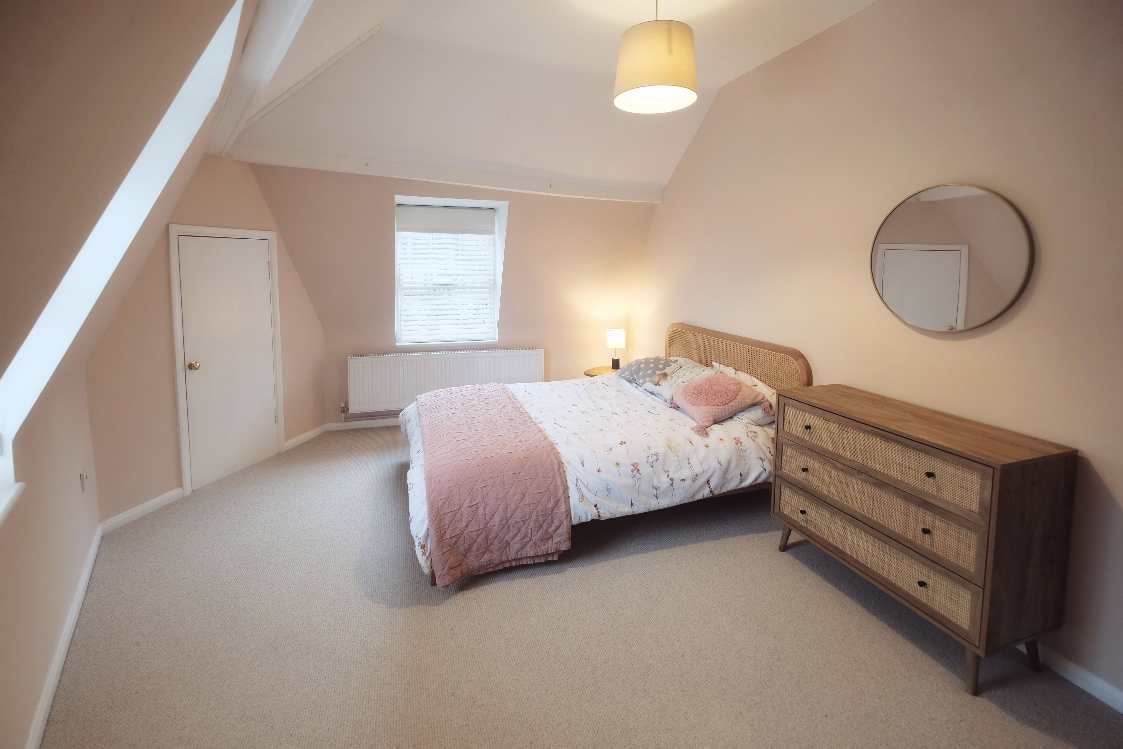 Une chambre à coucher avec un lit, une commode, une fenêtre et un luminaire au plafond.