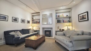 A modern living room with two sofas, a coffee table, a fireplace, bookshelves, and framed pictures on the walls. - Ramsgate - Coastal Cottage Escape - Pet Friendly with Parking (Ramsgate)